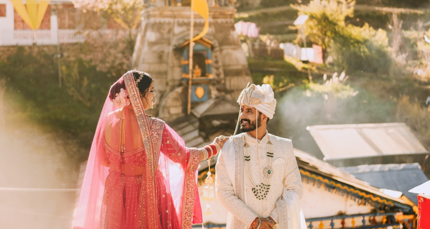 Bride and groom standing outside Triyuginarayan Temple during wedding rituals