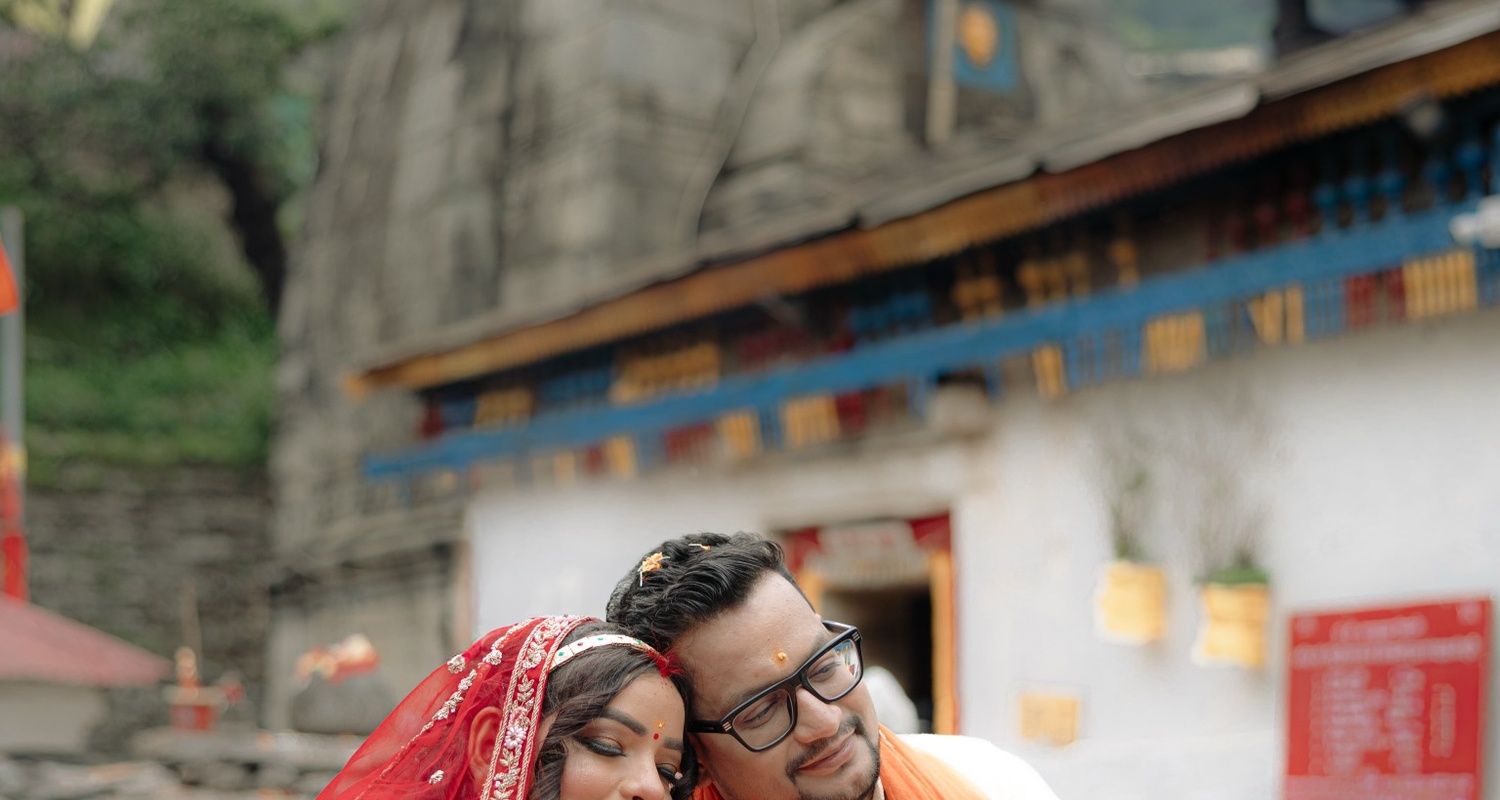 Couple portrait with temple architecture and mountain backdrop at Triyuginarayan